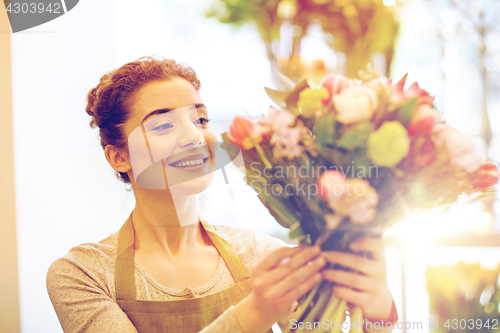 Image of smiling florist woman making bunch at flower shop