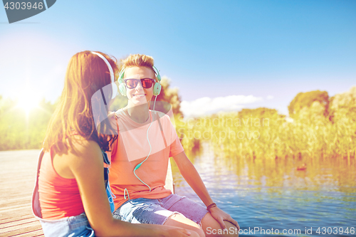 Image of happy teenage couple with earphones on river berth