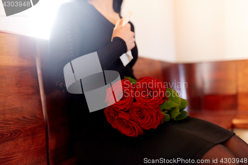 Image of close up of woman with roses at funeral in church