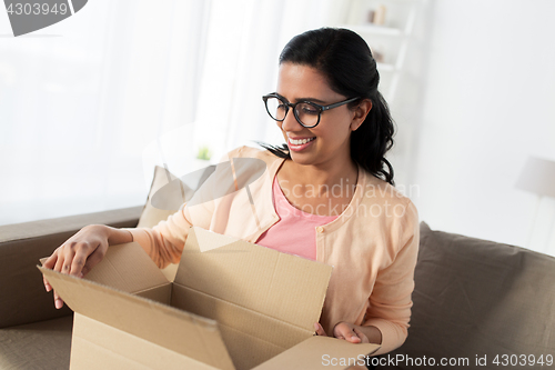 Image of happy young indian woman with parcel box at home