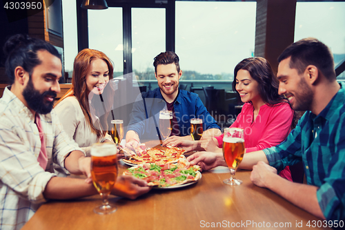 Image of friends eating pizza with beer at restaurant