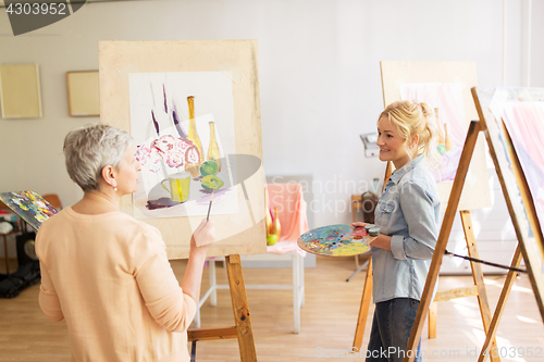 Image of artist women with easels painting at art school