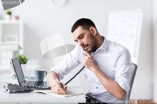 Image of businessman with pad calling on phone at office