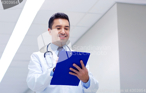 Image of smiling doctor with clipboard at hospital corridor