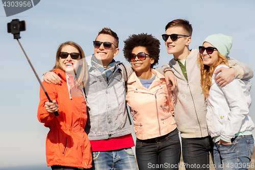 Image of happy friends taking selfie by smartphone outdoors