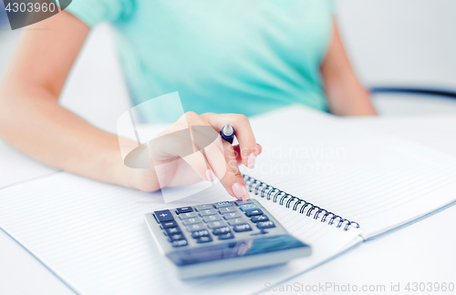 Image of businesswoman working with calculator in office