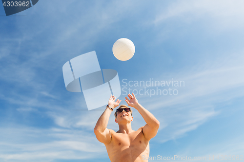 Image of young man with ball playing volleyball on beach