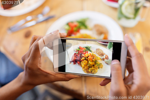 Image of hands with smartphone picturing food at restaurant