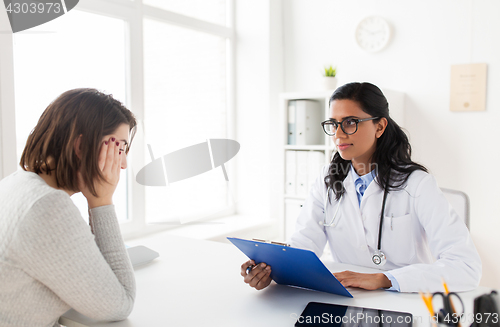 Image of doctor with clipboard and woman patient at clinic