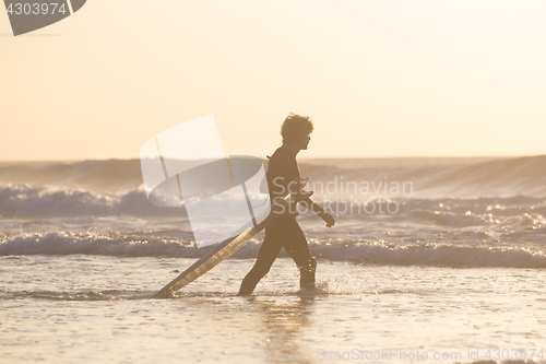 Image of Silhouette of surfer on beach with surfboard.