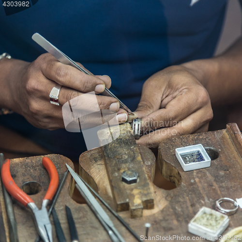 Image of Jeweler making handmade jewelry on vintage workbench.