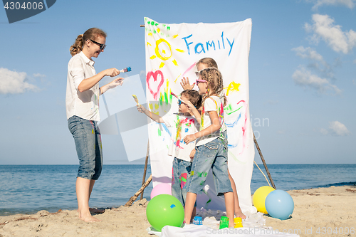 Image of Mother and children playing on the beach at the day time.