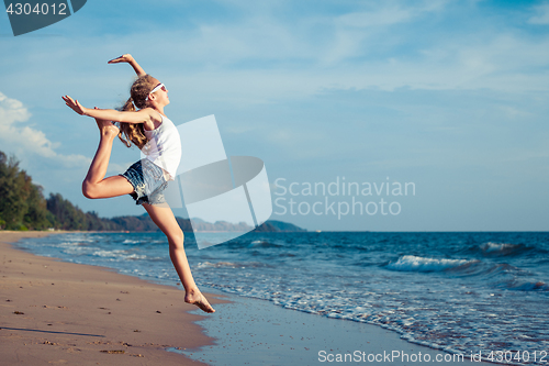 Image of One teen girl  jumping on the beach at the day time. 