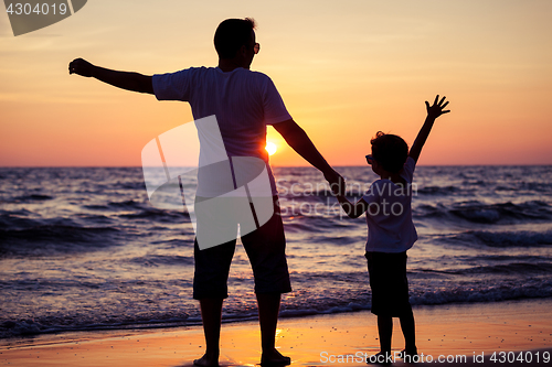 Image of Father and son playing in the park at the sunset time. People ha