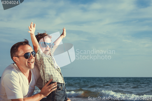 Image of Father and son playing on the beach at the day time.