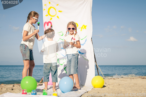 Image of Two sisters and brother playing on the beach at the day time.