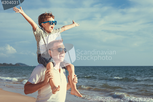 Image of Father and son playing on the beach at the day time.