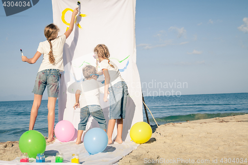 Image of Two sisters and brother playing on the beach at the day time.