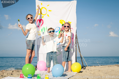 Image of Two sisters and brother playing on the beach at the day time.