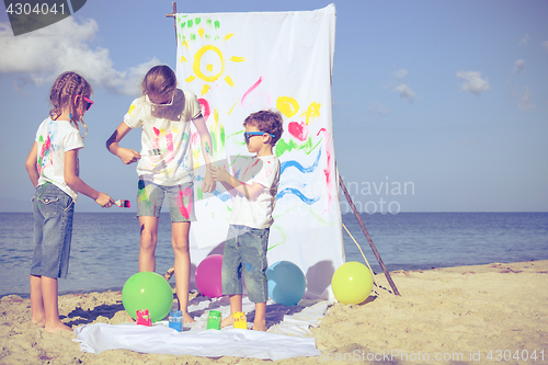 Image of Two sisters and brother playing on the beach at the day time.