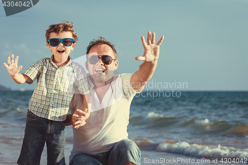 Image of Father and son playing on the beach at the day time.