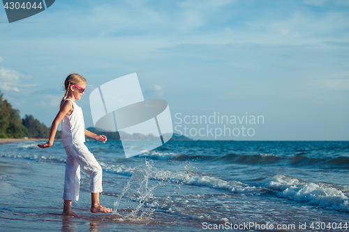 Image of Little girl  dancing on the beach at the day time.