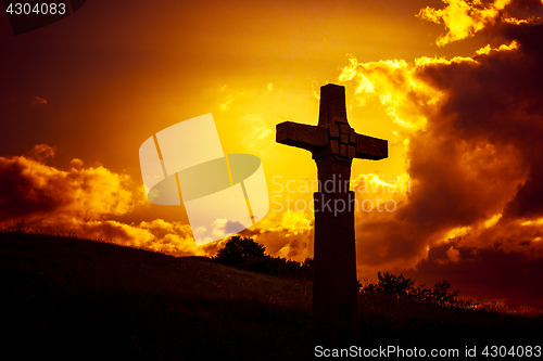 Image of a stone cross in front of a dramatic evening sky