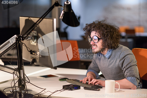 Image of man working on computer in dark startup office