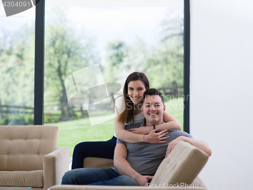 Image of young handsome couple hugging on the sofa