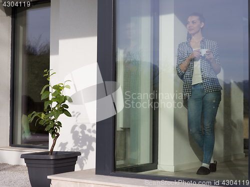 Image of young woman drinking morning coffee by the window