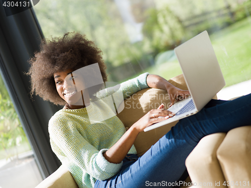 Image of African American woman using laptop on sofa