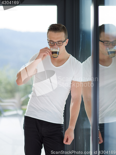 Image of young man drinking morning coffee by the window