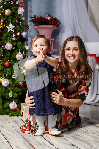 Image of Little girl With her happy mother at studio with christmas decorations