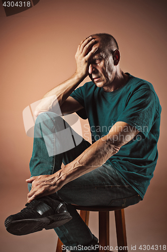 Image of Worried mature man touching his head.