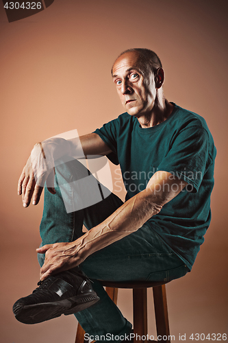 Image of Worried mature man sitting at studio