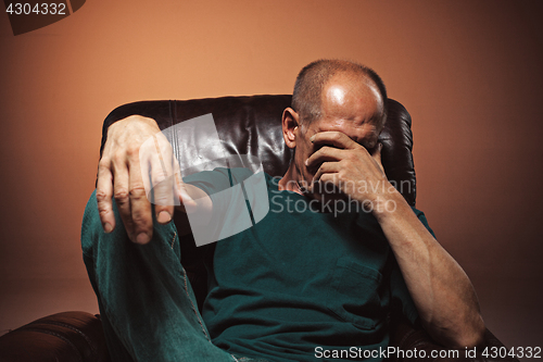 Image of Worried mature man touching his head.