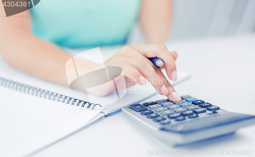 Image of businesswoman working with calculator in office