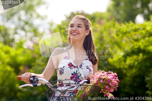 Image of happy woman riding fixie bicycle in summer park