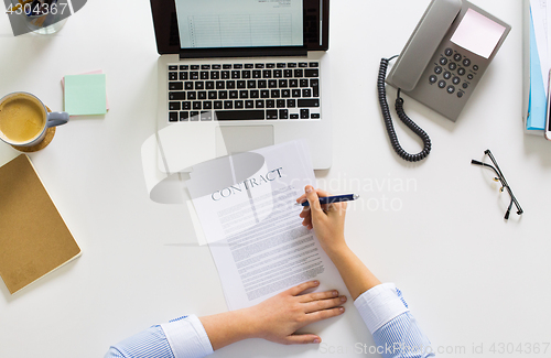 Image of businesswoman signing contract document at office