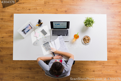 Image of woman with calculator and papers at office table