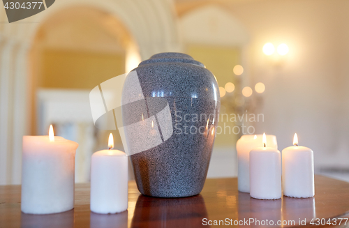 Image of cremation urn and candles burning in church