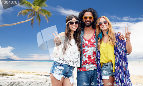 Image of happy hippie friends showing peace on summer beach