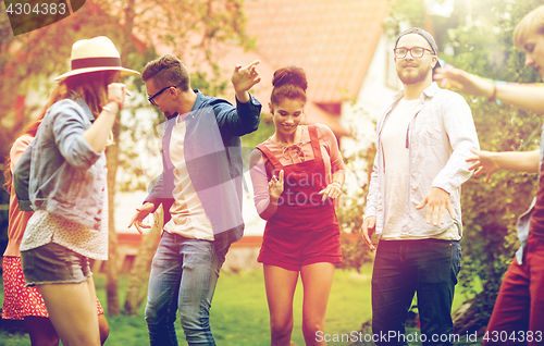 Image of happy friends dancing at summer party in garden