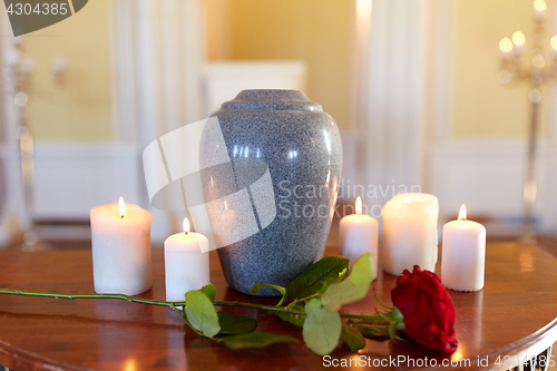 Image of red rose and cremation urn with burning candles