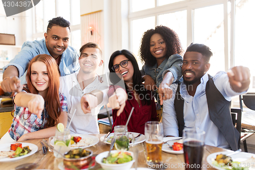 Image of happy friends eating at restaurant
