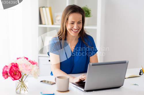 Image of happy woman with laptop working at home or office