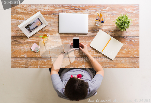 Image of woman with smartphone and laptop at office table