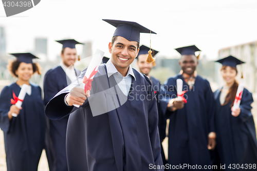 Image of happy students in mortar boards with diplomas