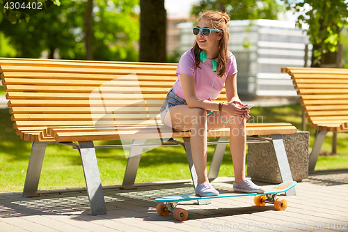 Image of happy teenage girl with headphones and longboard