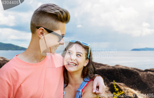 Image of happy teenage couple hugging outdoors